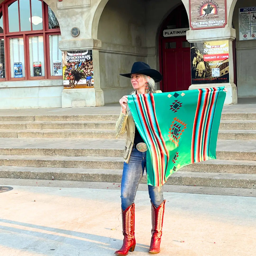 Western Silk Scarf - Cowgirl holding a Cowtown Wild Rags turquoise serape silk scarf with tan, maroon, and coral.