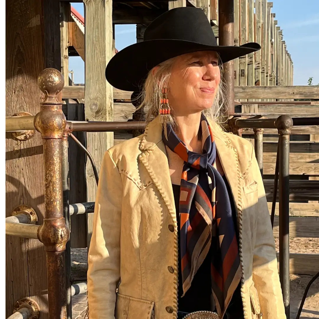 Cowgirl wearing a Cowtown Wild Rags Aztec silk scarf with navy blue, soft tan, copper, and charcoal gray in the Fort Worth Stockyards.