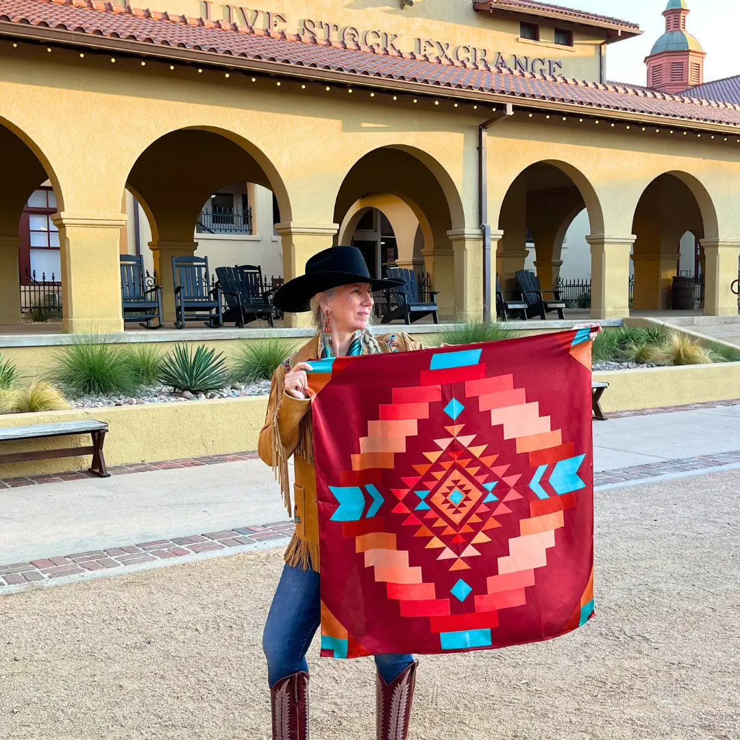 A cowgirl holding a maroon wild rag silk scarf with copper and turquoise in the Fort Worth Stockyards. 