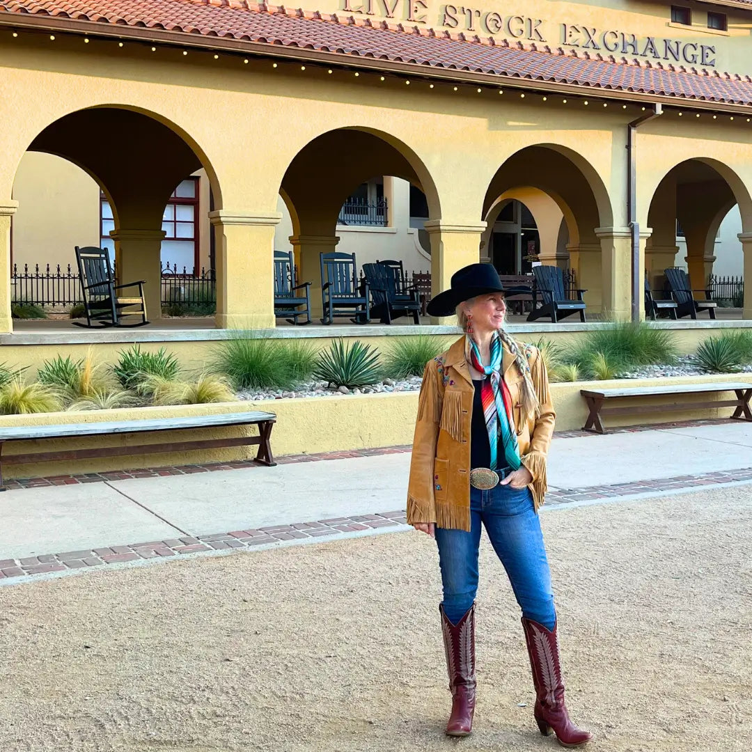 Cowgirl wearing a Cowtown Wild Rags turquoise serape silk scarf with blue, tan, maroon, orange and, coral in the Fort Worth Stockyards.