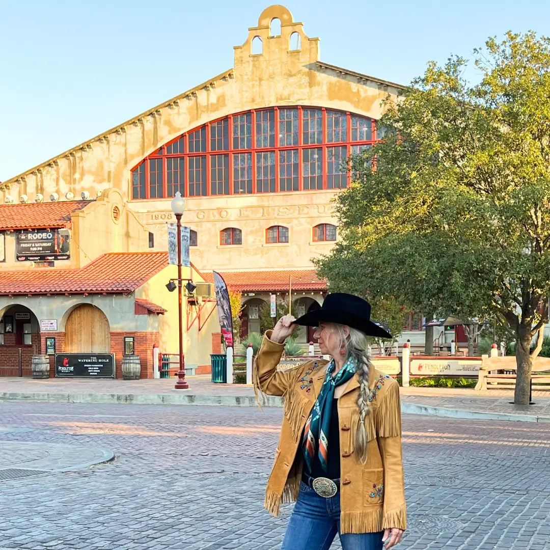 Cowgirl is wearing a teal blue and turquoise silk scarf wild rag in the Fort Worth Stockyards.