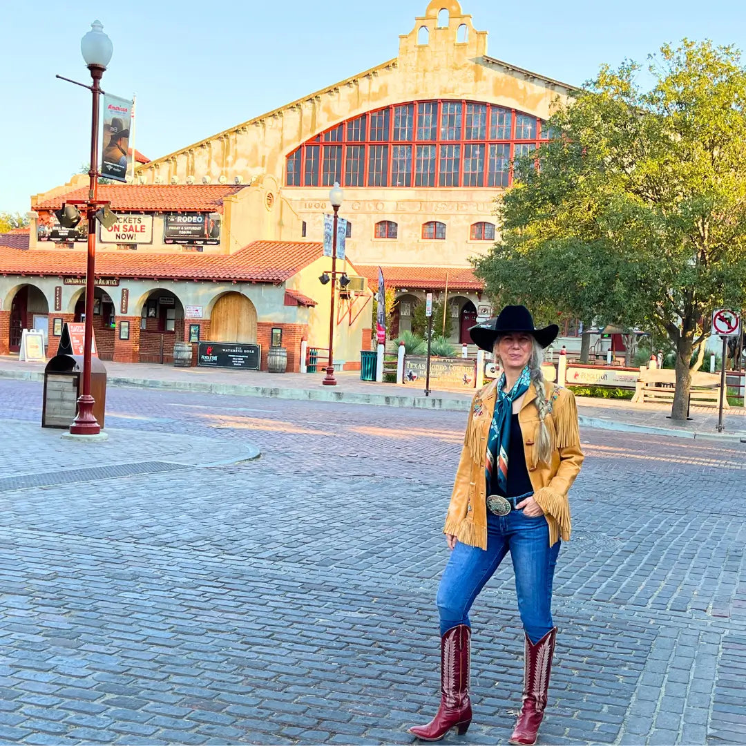 Cowgirl is wearing a teal blue and turquoise silk scarf wild rag in the Fort Worth Stockyards.