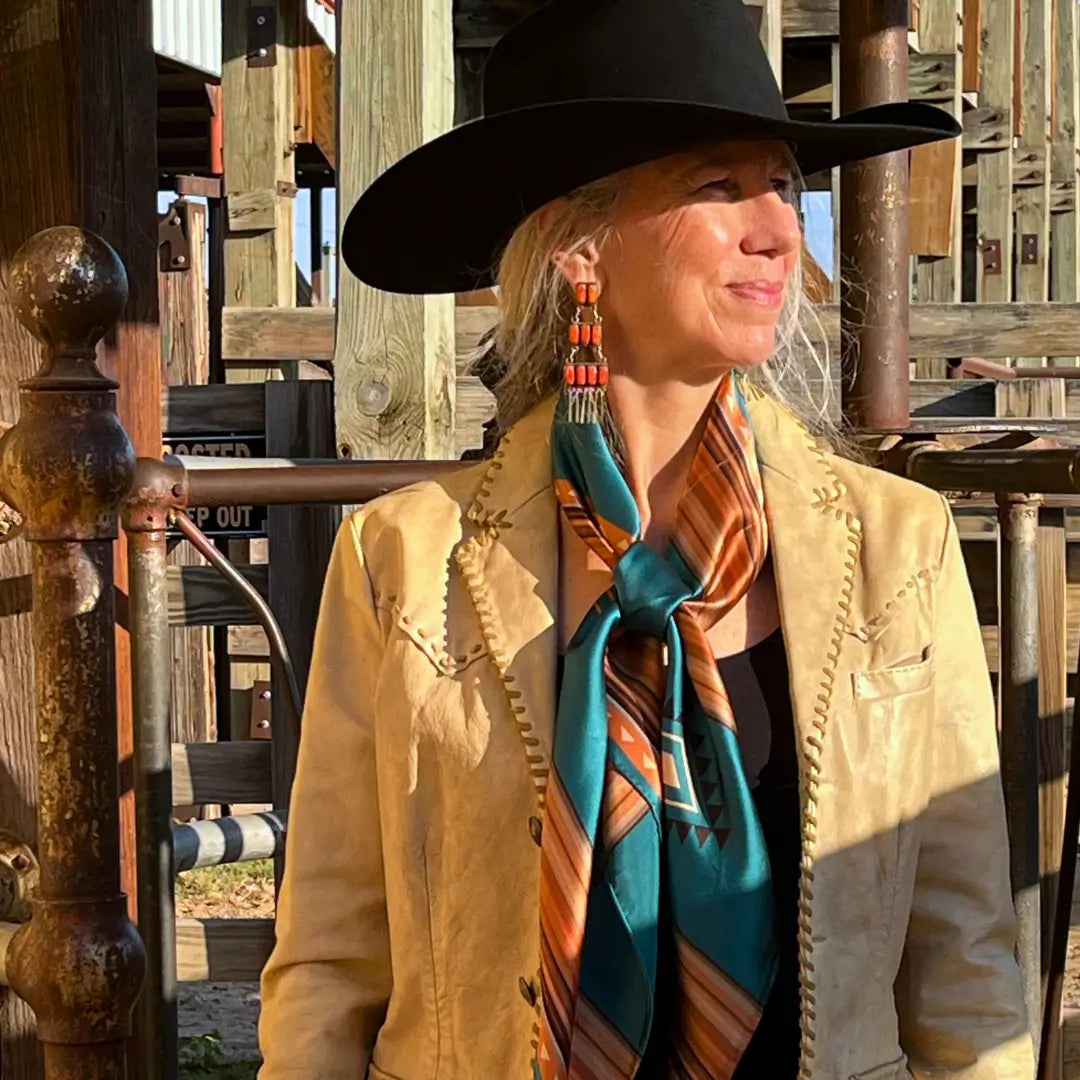 Cowgirl is wearing a southwestern teal blue and copper silk scarf wild rag in the Fort Worth Stockyards.