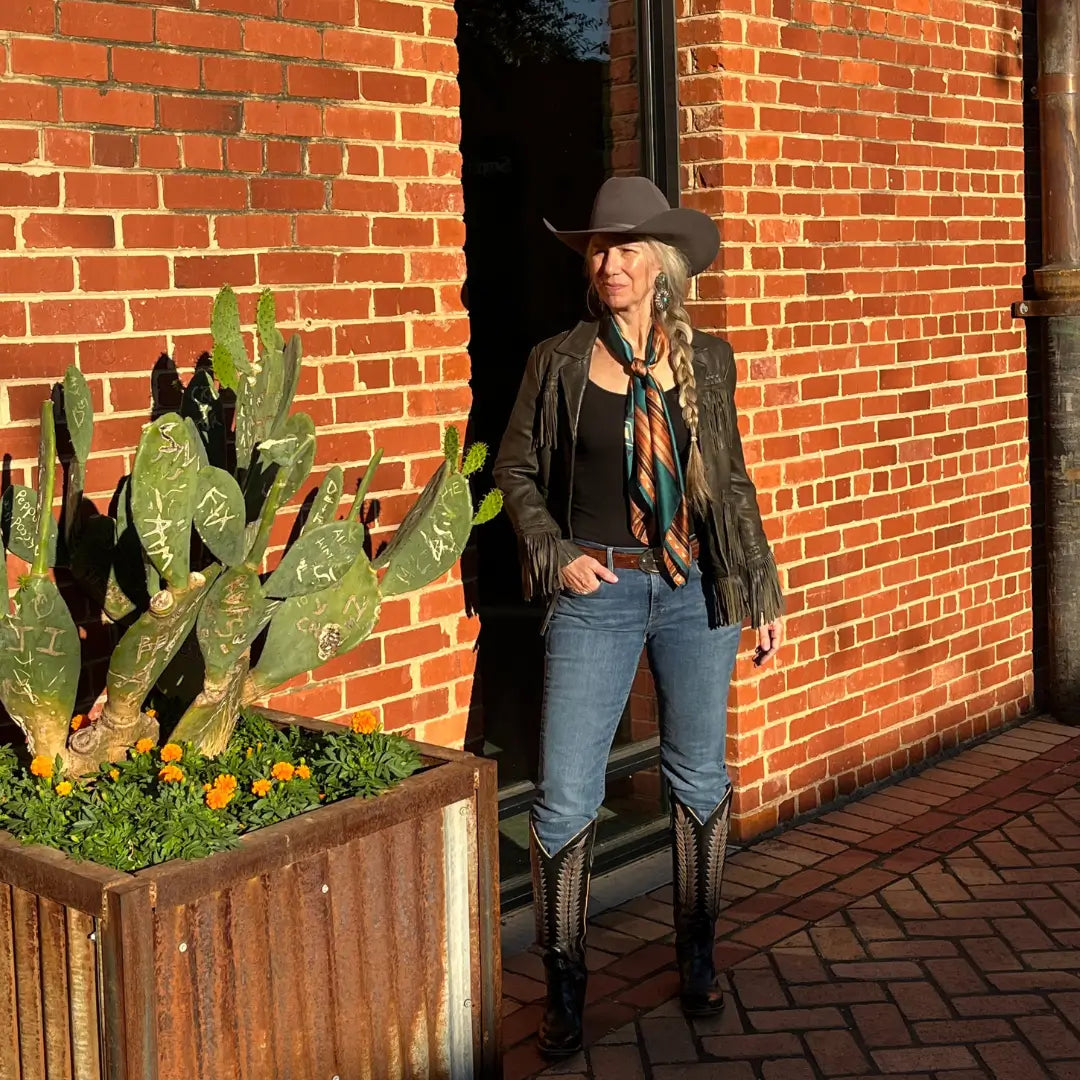 Cowgirl is wearing a southwestern teal blue and copper silk scarf wild rag in the Fort Worth Stockyards.