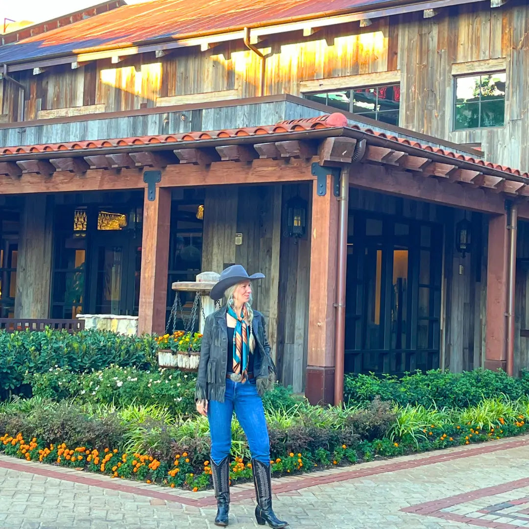 Cowgirl is wearing a southwestern teal blue and copper silk scarf wild rag in the Fort Worth Stockyards.