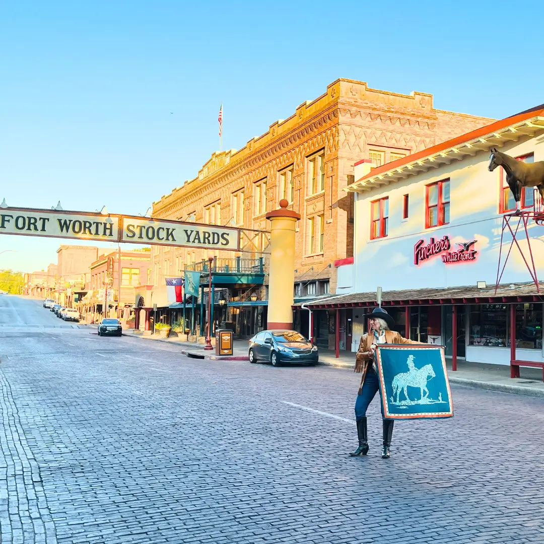 Cowgirl holding a teal blue and turquoise silk scarf wild rag in the Fort Worth Stockyards.