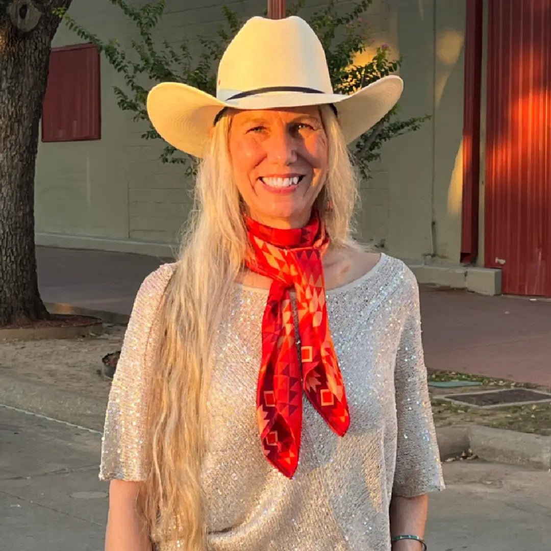 A cowgirl wearing an Aztec wild rag silk scarf with red, maroon, copper and peach in the Fort Worth Stockyards.