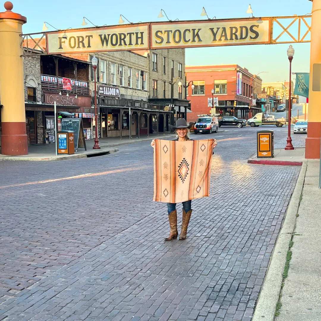 Cowgirl is holding a southwestern soft brown and copper silk scarf wild rag in the Fort Worth Stockyards. 