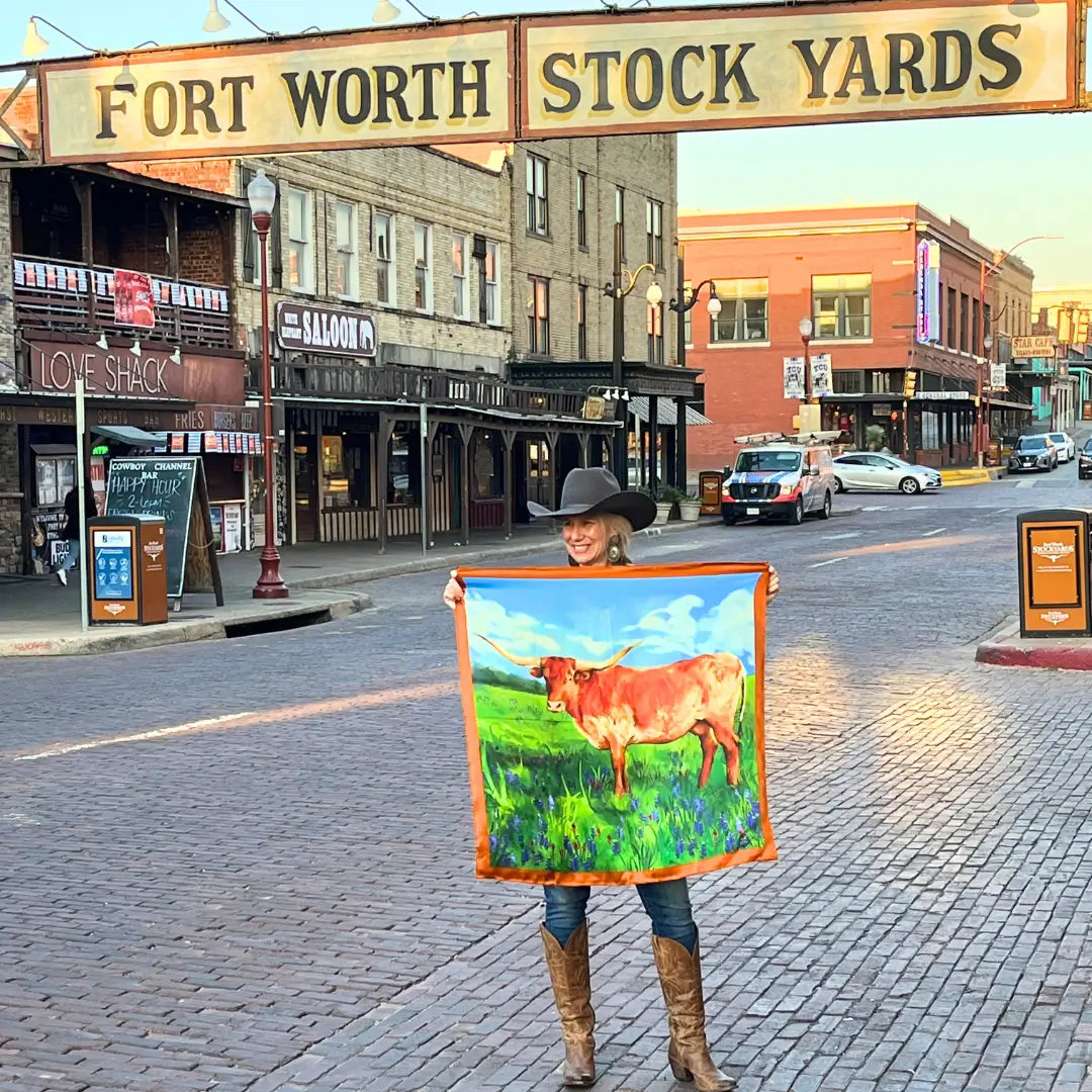 Cowgirl is holding a longhorn silk scarf wild rag in the Fort Worth Stockyards.