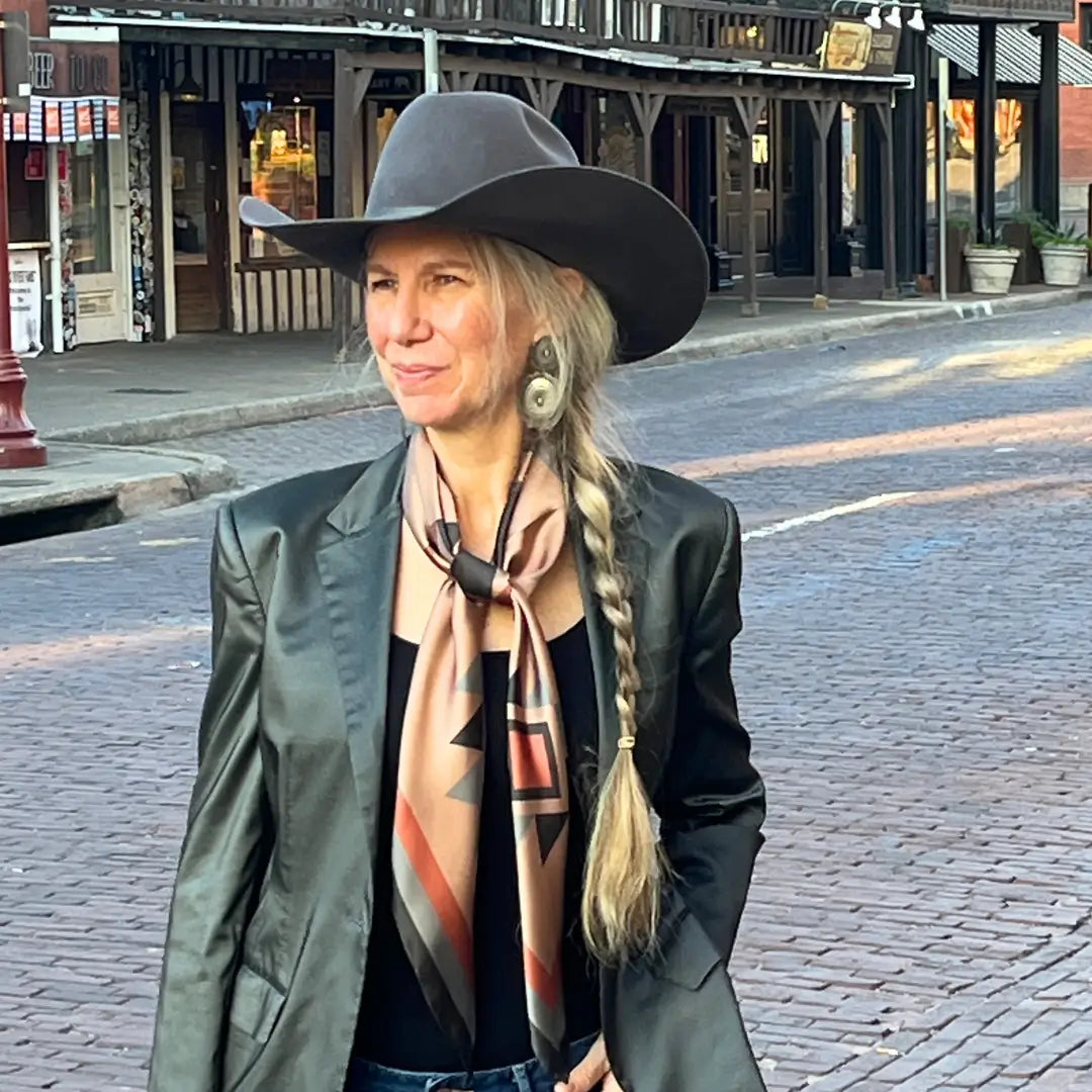 Cowgirl wearing Cowtown Wild Rags Aztec silk scarf with dusty pink, charcoal and soft gray in the Fort Worth Stockyards.