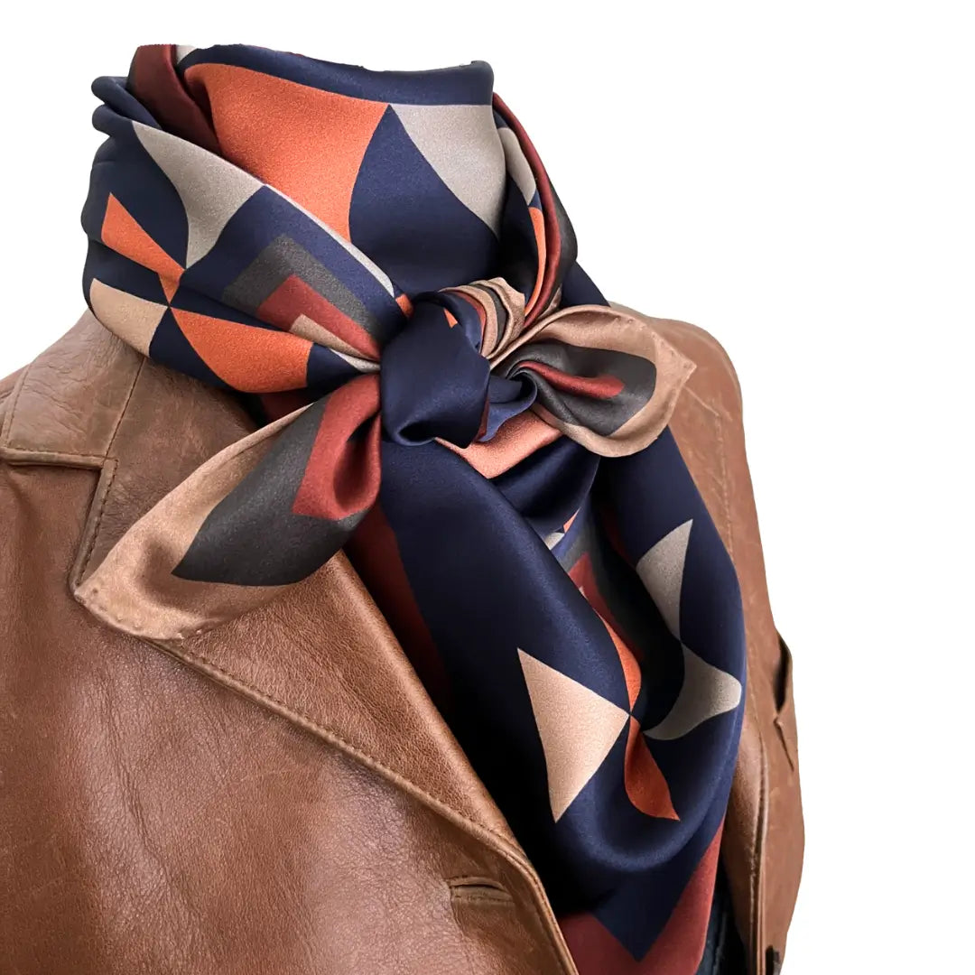 Close-up of Cowtown Wild Rags with a large Aztec silk scarf with navy blue, soft tan, copper, and charcoal gray.