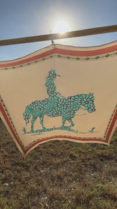 Video of a soft tan and turquoise design silk scarf wild rag that is a cowgirl riding a horse.